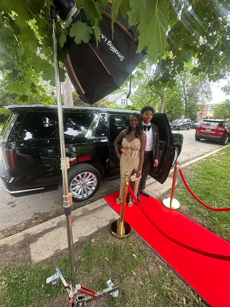 Prom client posing on the red carpet beside the SUV